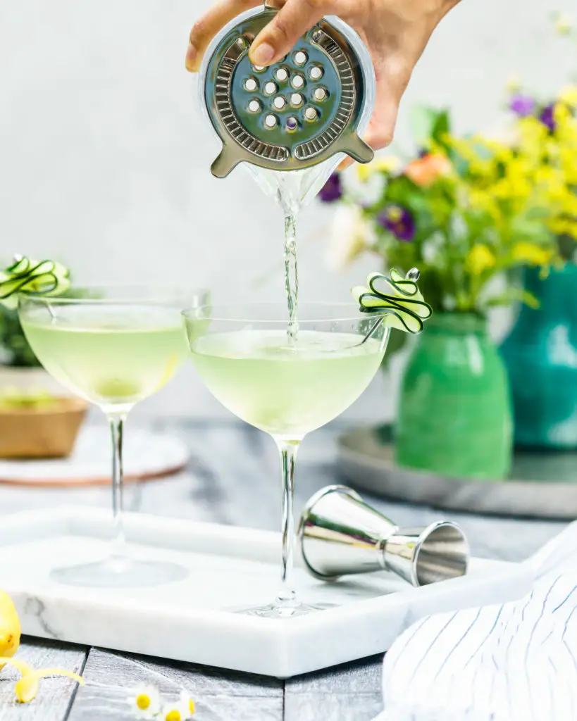 Straining Summer Cucumber Dirty Martini into Glass