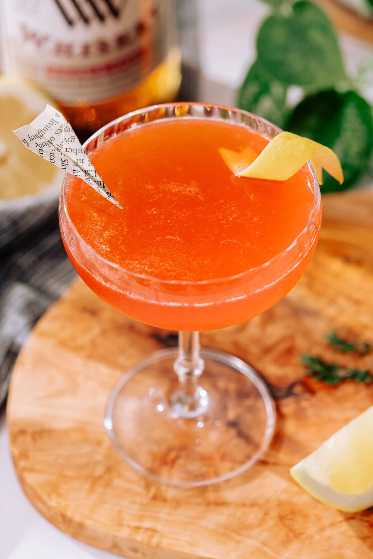 Paper Plane cocktail in a coupe glass with a lemon twist and paper plane garnish