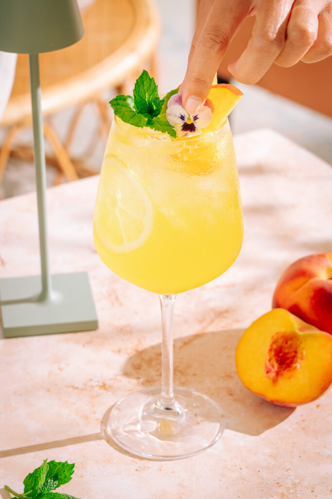 Placing an edible flower on the Amalfi Spritz Peach Limoncello Cocktail