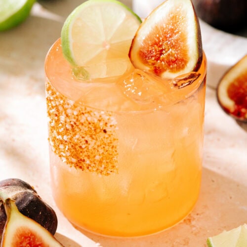 close up of maple fig margarita, with a slice of lime and half fig as a garnish. The rim is coated with a mixture of salt, sugar, and cinnamon.