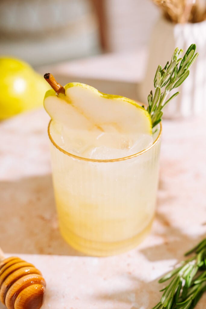 overview shot of the rosemary pear mocktail. it's garnished with a pear slice and sprig of rosemary.