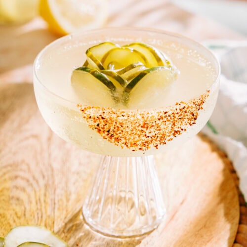 pickle cocktail with a pickle ice cube, tajin rim on a table