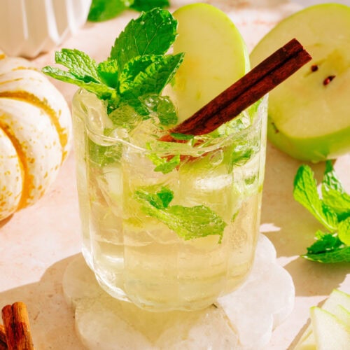 Non-alcoholic hugo spritz in glass with apples, mint and cinnamon