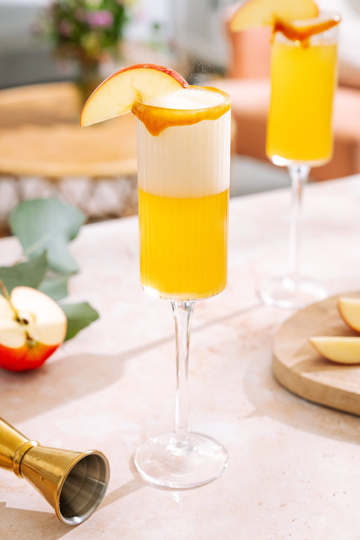 Bubbling Caramel apple mimosa with caramel rim, garnished with apple slice.