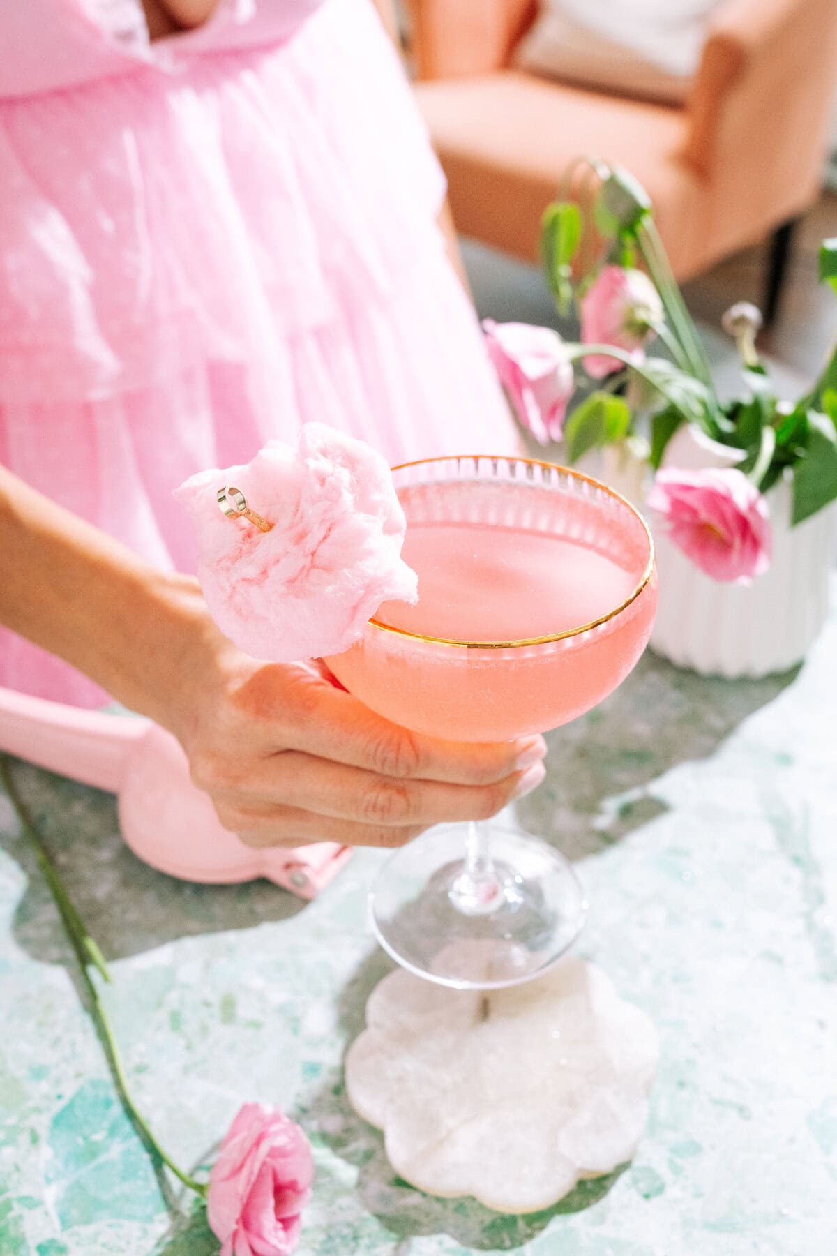 Hand holding pink oz-mopolitan wicked cocktail with cotton candy garnish