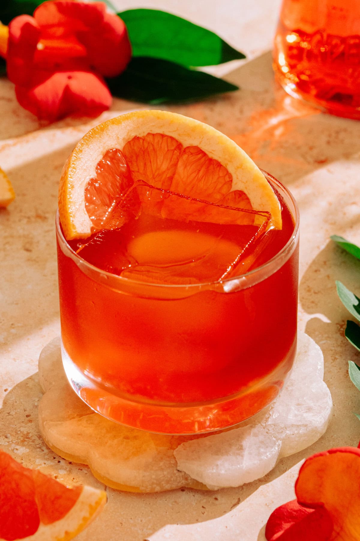 Aperol Negroni in a short glass with large ice cube garnished with slice of grapefruit.