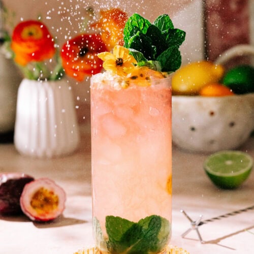 Passion Fruit Swizzle Mocktail (With Hibiscus Tea) garnished with mint leaves and flying powered sugar.