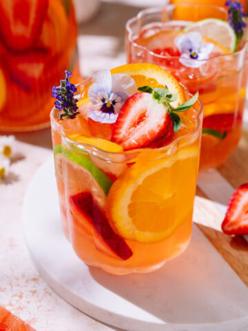 Summer fruit sangria with strawberries, citrus slices, and edible flowers.