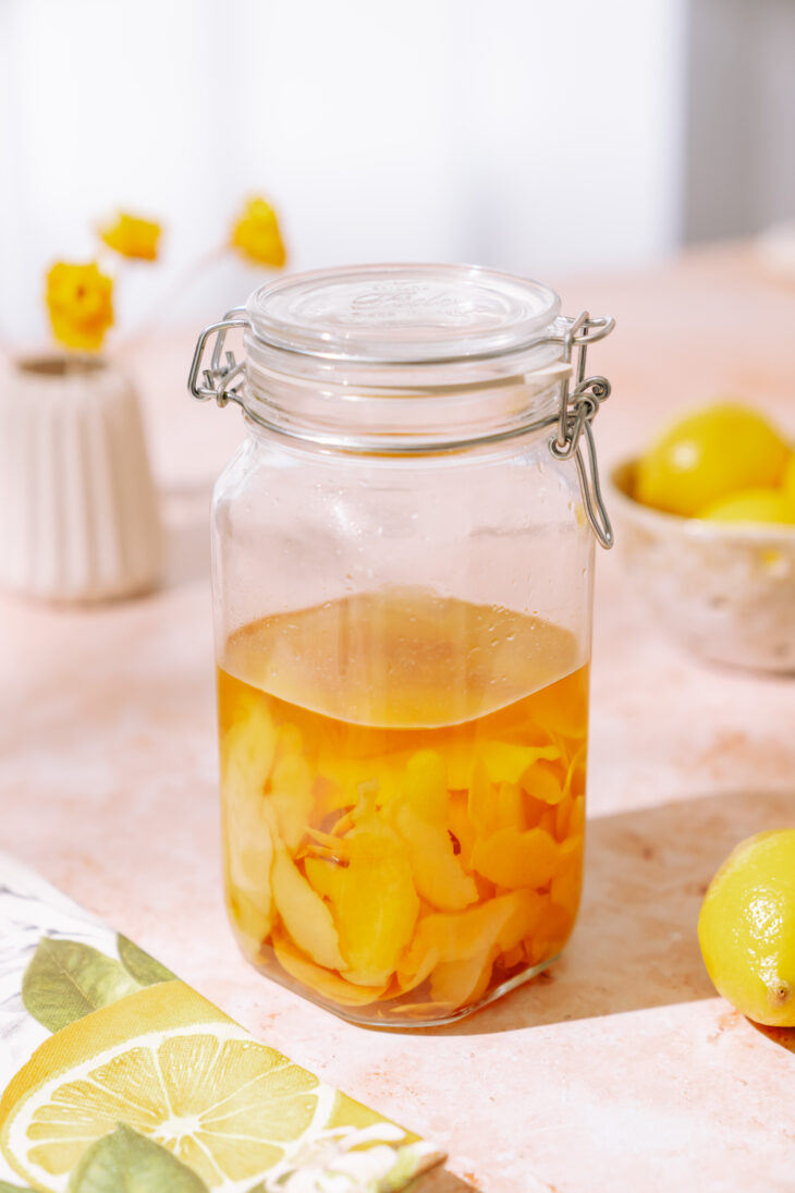 Lemon peels infusing in jar with liquor for homemade limoncello recipe