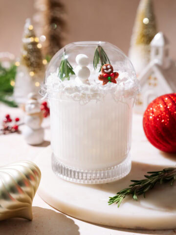 White Snow Globe Margarita topped with a clear dome, mini snowman, rosemary trees, and a gingerbread figure.