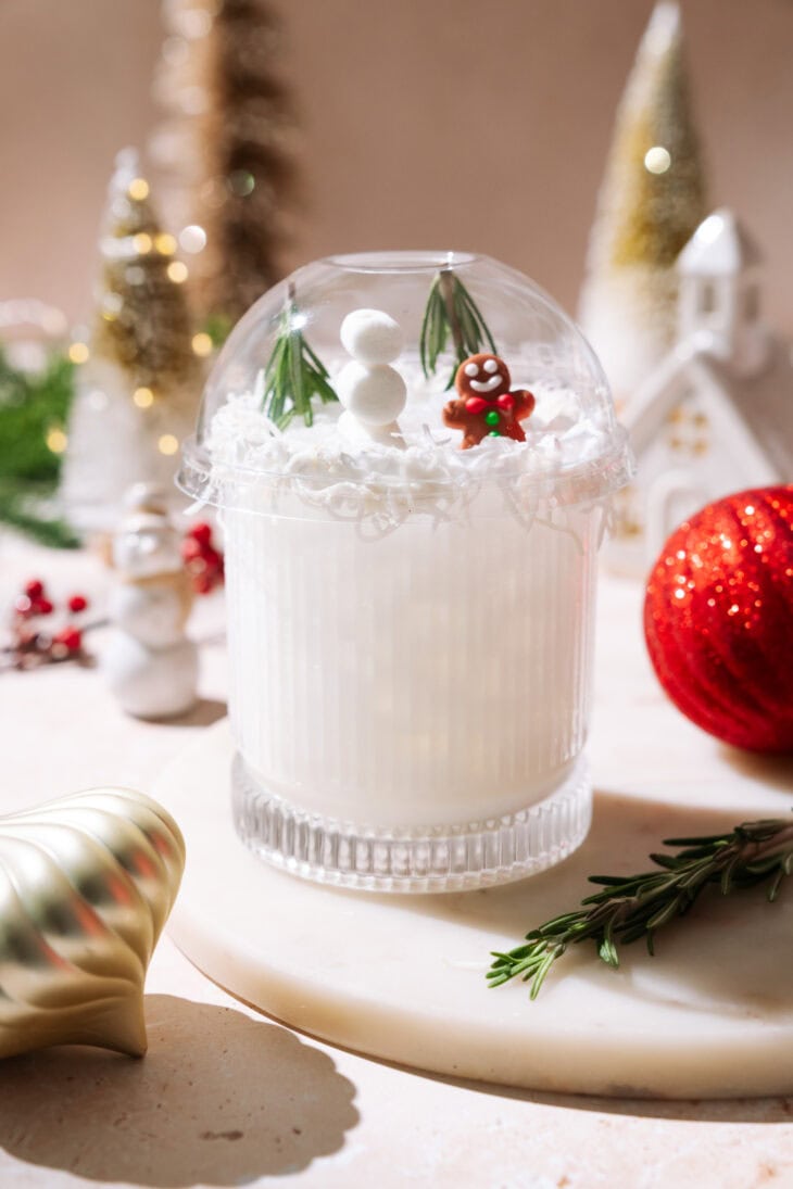 White Snow Globe Margarita topped with a clear dome, mini snowman, rosemary trees, and a gingerbread figure.