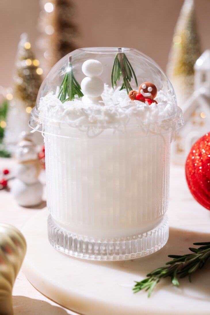 White Snow Globe Margarita topped with a clear dome, mini snowman, rosemary trees, and a gingerbread figure.