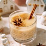Easy eggnog cocktail garnished with cinnamon stick and star anise in a festive glass.