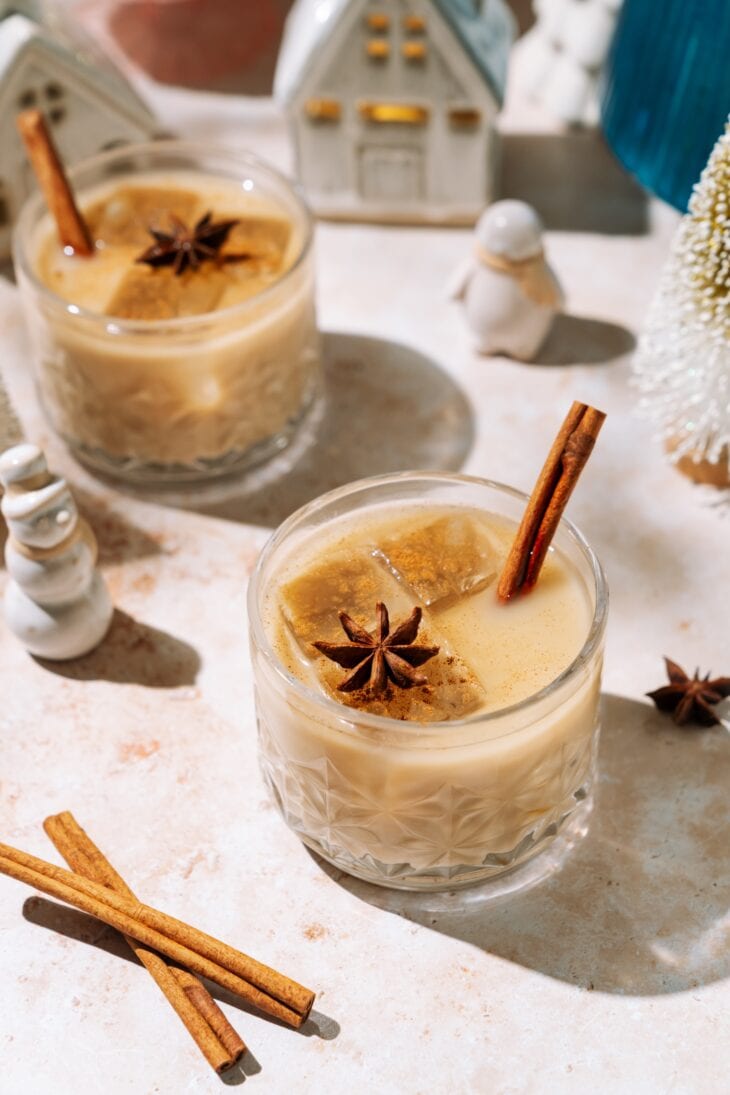 Easy eggnog cocktail garnished with cinnamon stick and star anise in a festive glass.