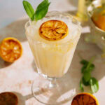 Creamy limoncello cocktail in a vintage glass, garnished with charred lemon and fresh sage.