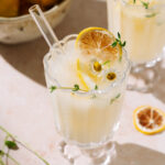 Refreshing creamy limoncello spritz with citrus, fresh herbs, and chamomile flowers over ice