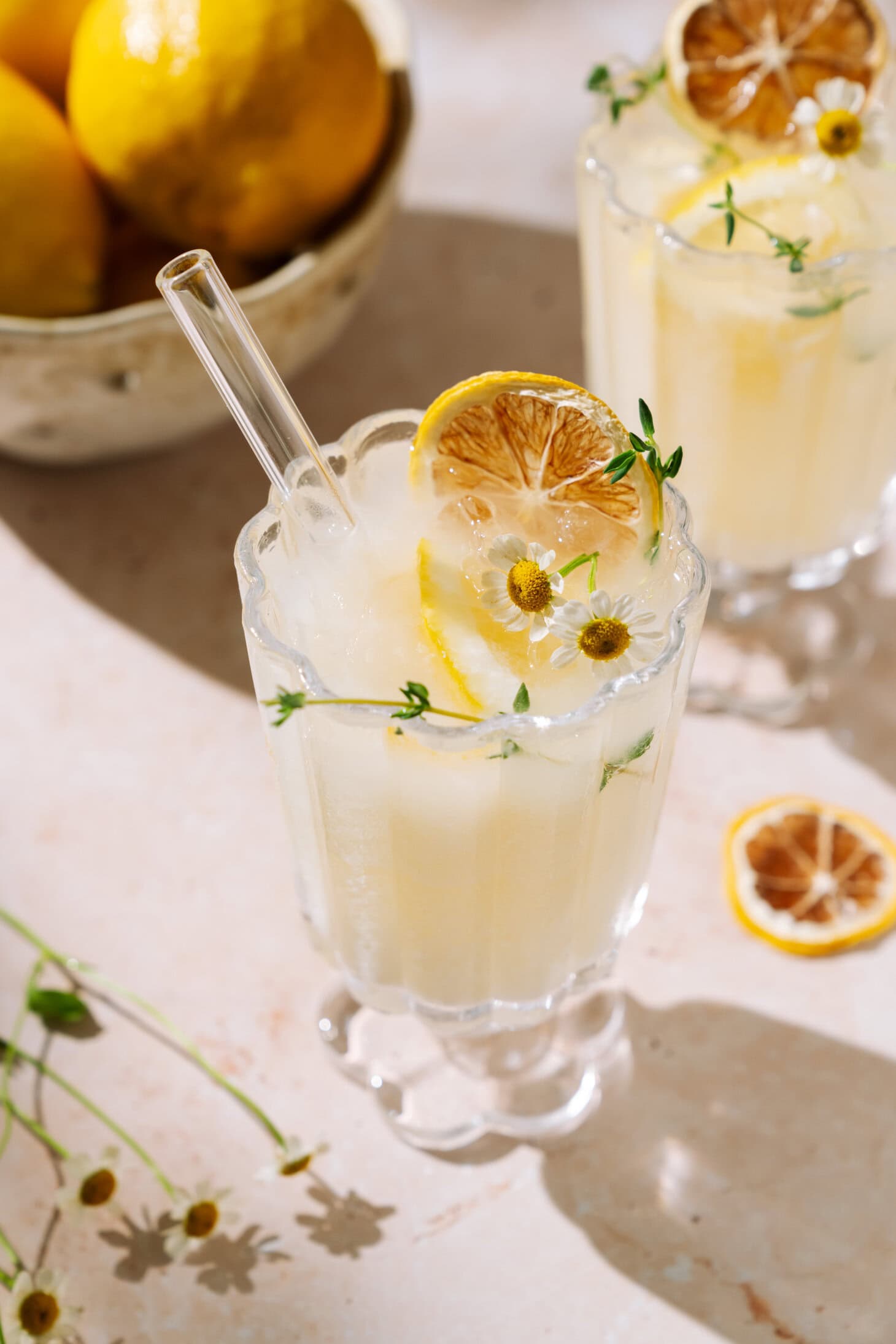 Refreshing creamy limoncello spritz with citrus, fresh herbs, and chamomile flowers over ice