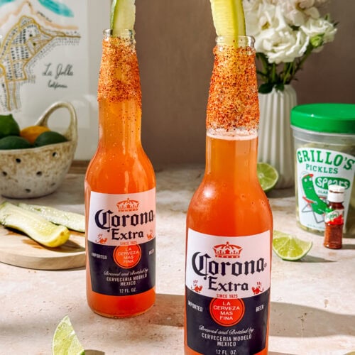 Refreshing Clamato michelada with lime, chili-salt rim, and pickle garnish in a chilled beer bottle, perfect for a spicy, tangy summer drink.