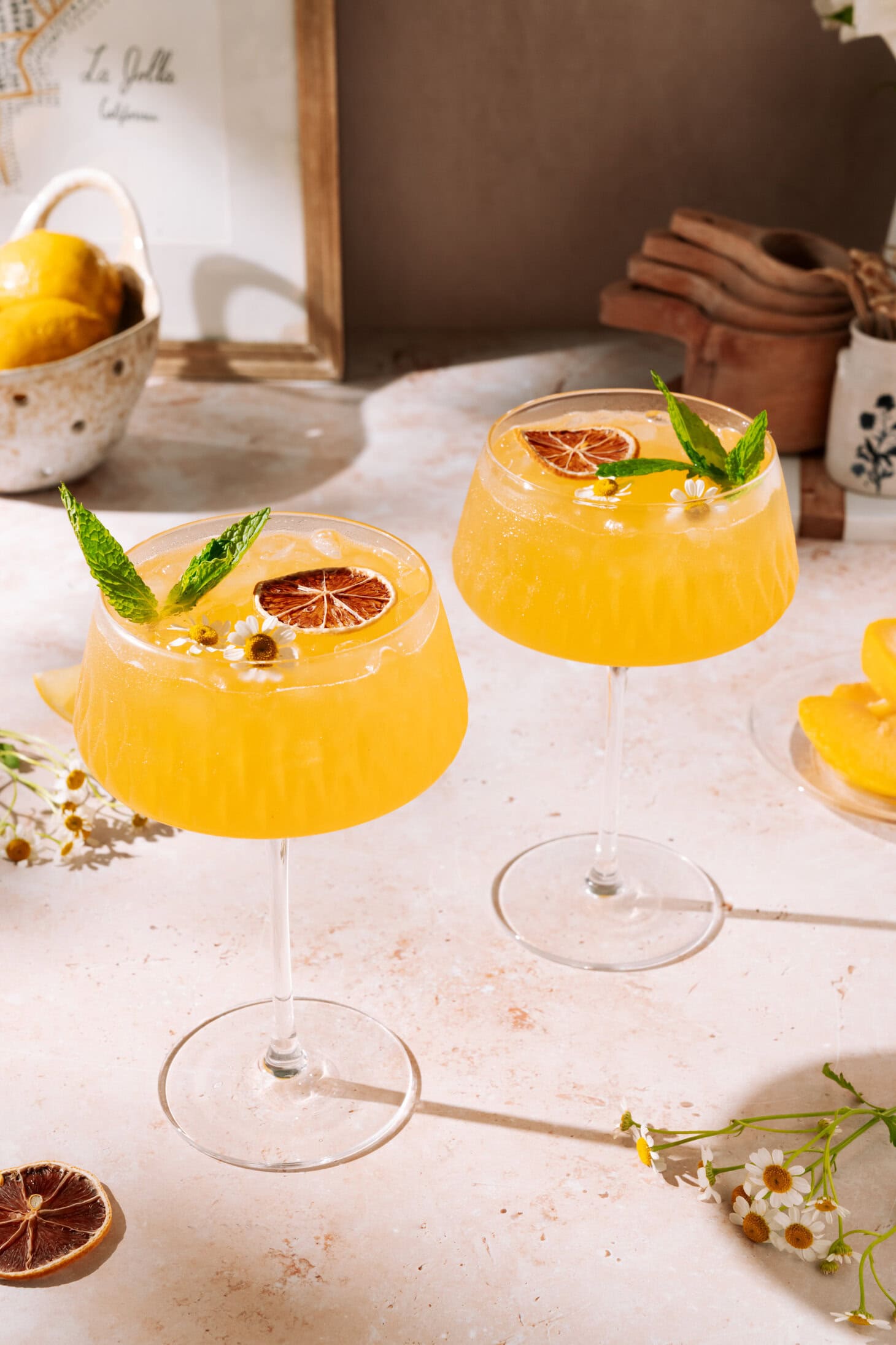 Bright and refreshing Ginger Peach Mocktail with fresh mint, dried orange slice, and edible flowers, served over ice in a stylish coupe glass.