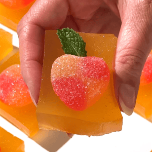 Peach Bellini jello shots topped with sugared peach slices and fresh mint.