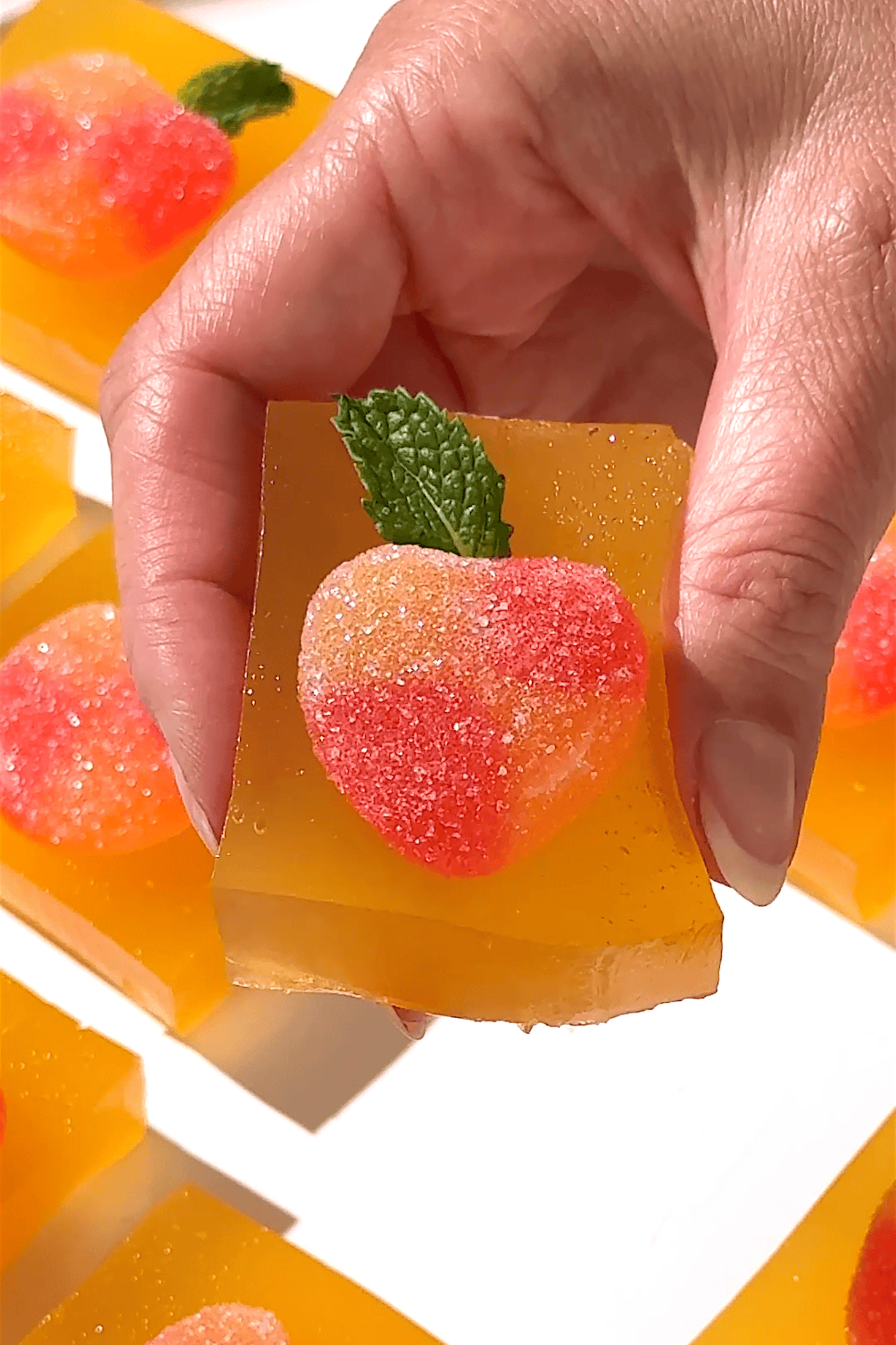 Peach Bellini jello shots topped with sugared peach slices and fresh mint.