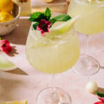 Honeydew Spritz with Limoncello in a tall glass, garnished with fresh mint, honeydew melon balls, and an edible flower.