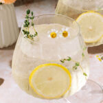 Limoncello Spritz with fresh lemon slices and floral herb garnish.