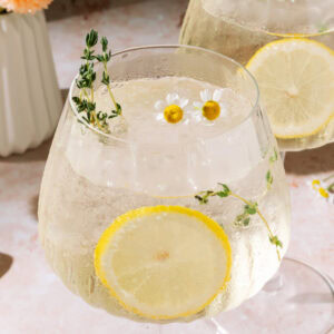 Limoncello Spritz with fresh lemon slices and floral herb garnish.