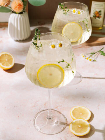 Limoncello Spritz with fresh lemon slices and floral herb garnish.