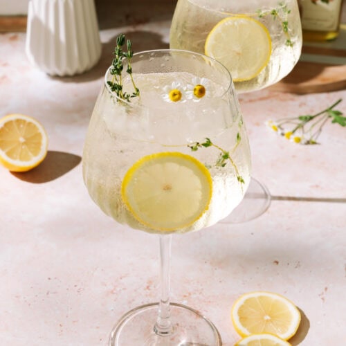 Limoncello Spritz with fresh lemon slices and floral herb garnish.