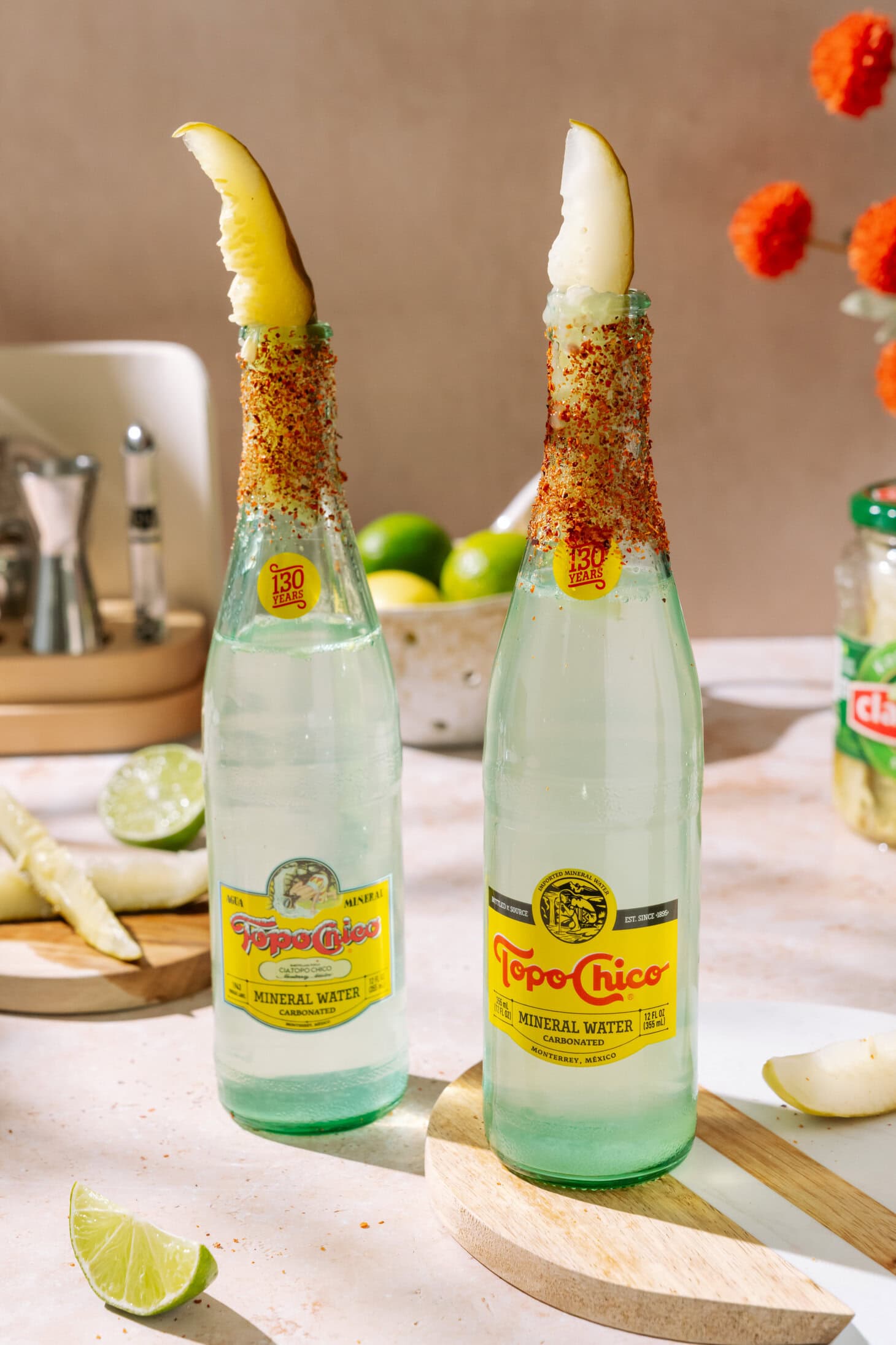 Two bottles Pickle Ranch Water cocktail with lime, chili seasoning, and a pickle spear garnish.