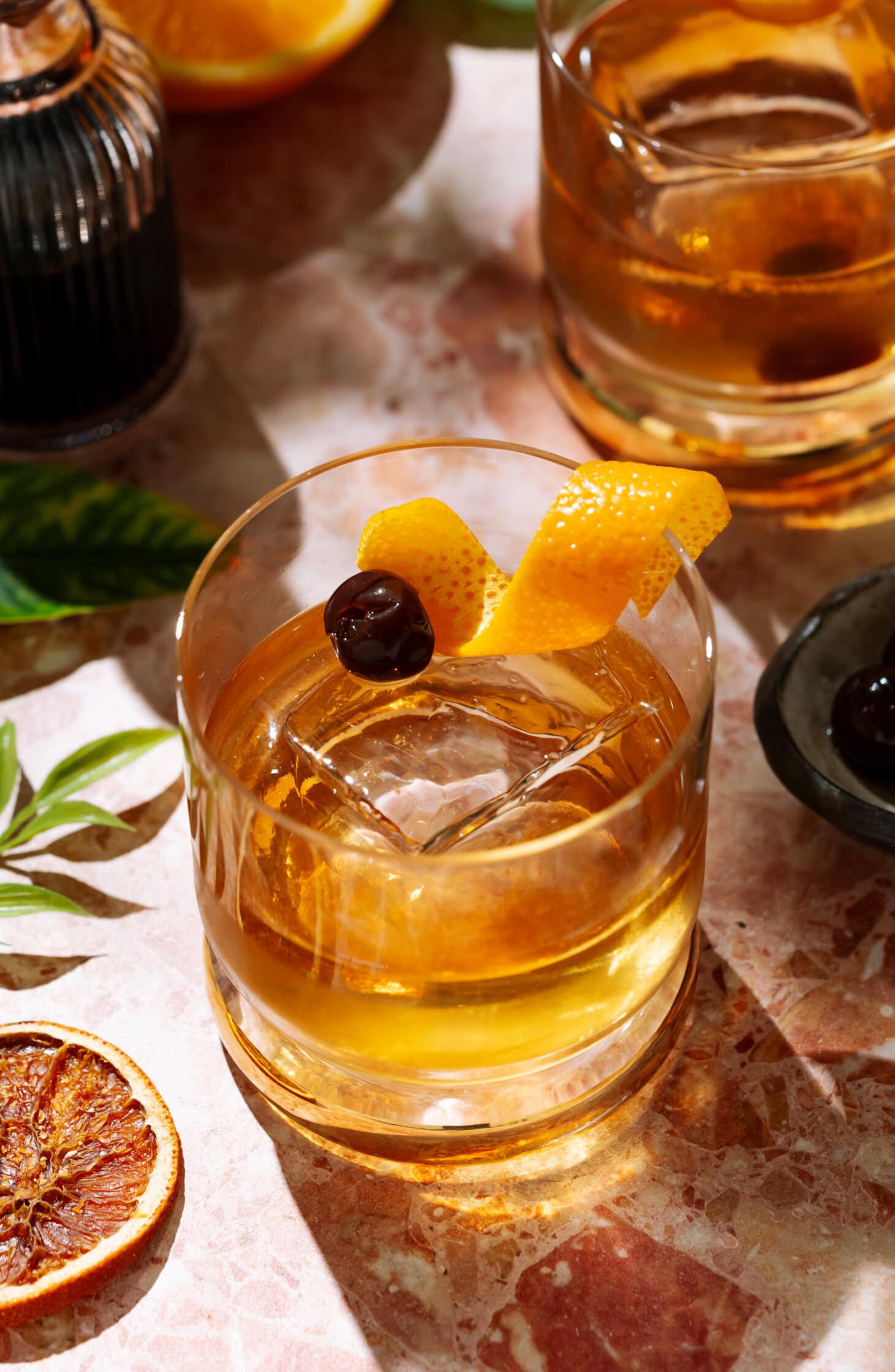 Añejo Tequila Old Fashioned cocktail in a short glass over ice, garnished with an orange twist and cherry.