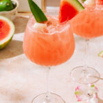 Lychee Watermelon Mocktail garnished with fresh watermelon slices and tropical flowers.