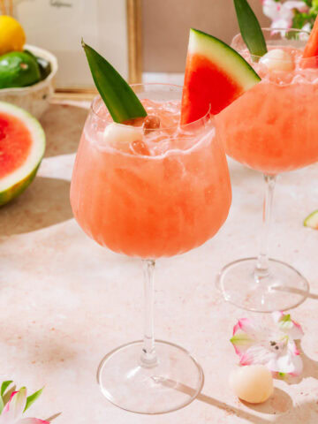 Lychee Watermelon Mocktail garnished with fresh watermelon slices and tropical flowers.