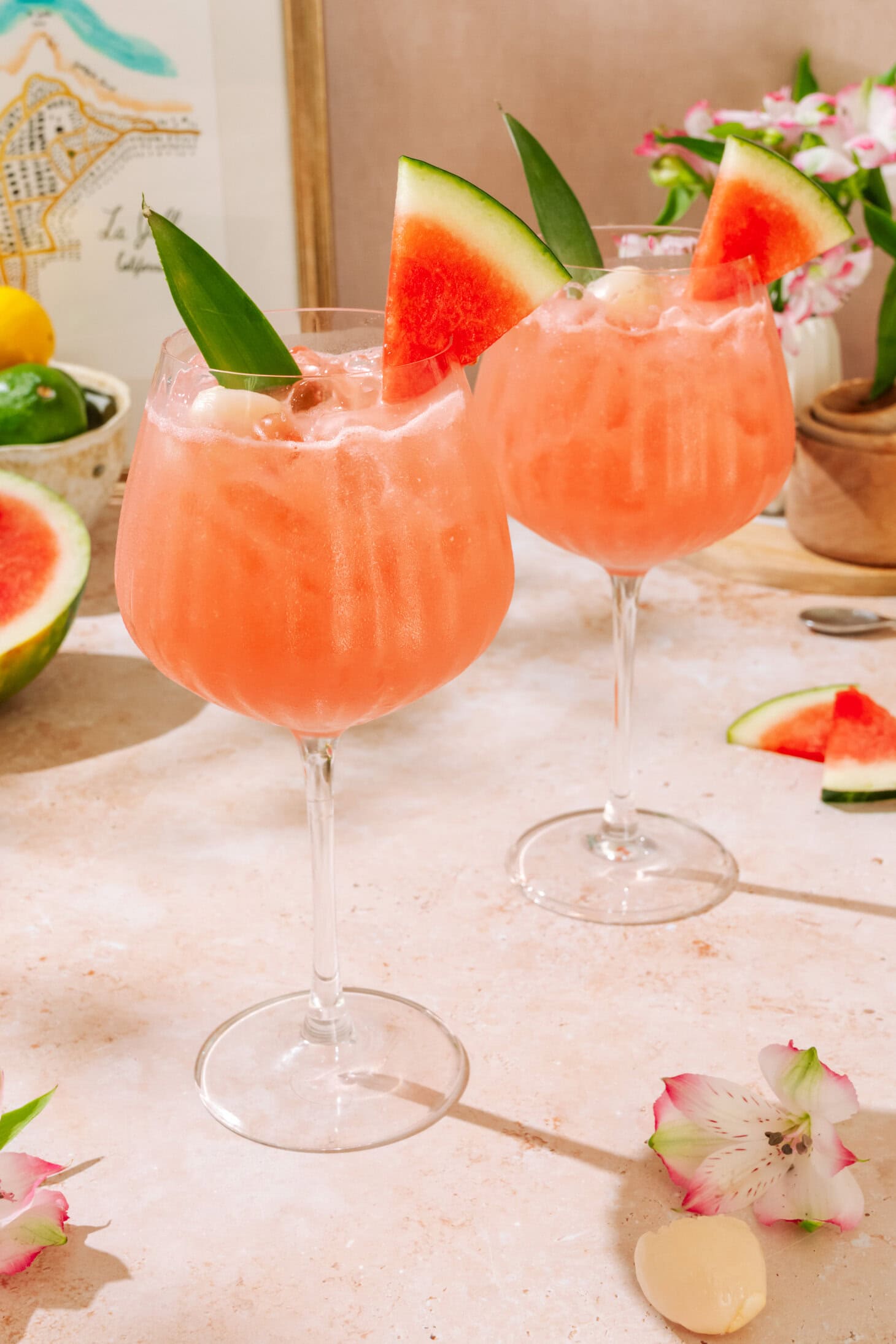 Lychee Watermelon Mocktail garnished with fresh watermelon slices and tropical flowers.