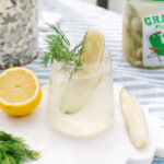 Pickle Spritz in a short glass, garnished with a pickle slice, fresh dill, and lemon.