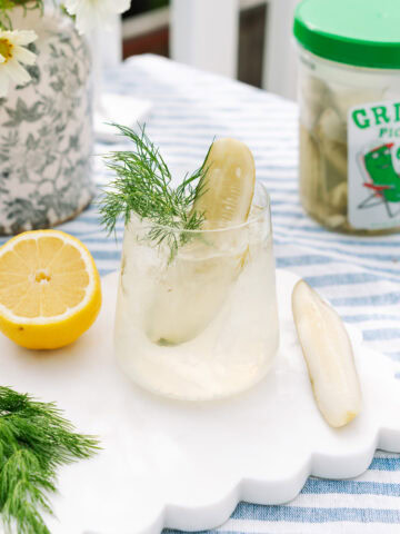 Pickle Spritz in a short glass, garnished with a pickle slice, fresh dill, and lemon.