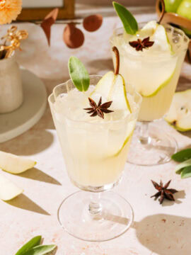 Pear White Wine Spritzer in stemmed glasses, garnished with fresh pear, sage, and star anise.