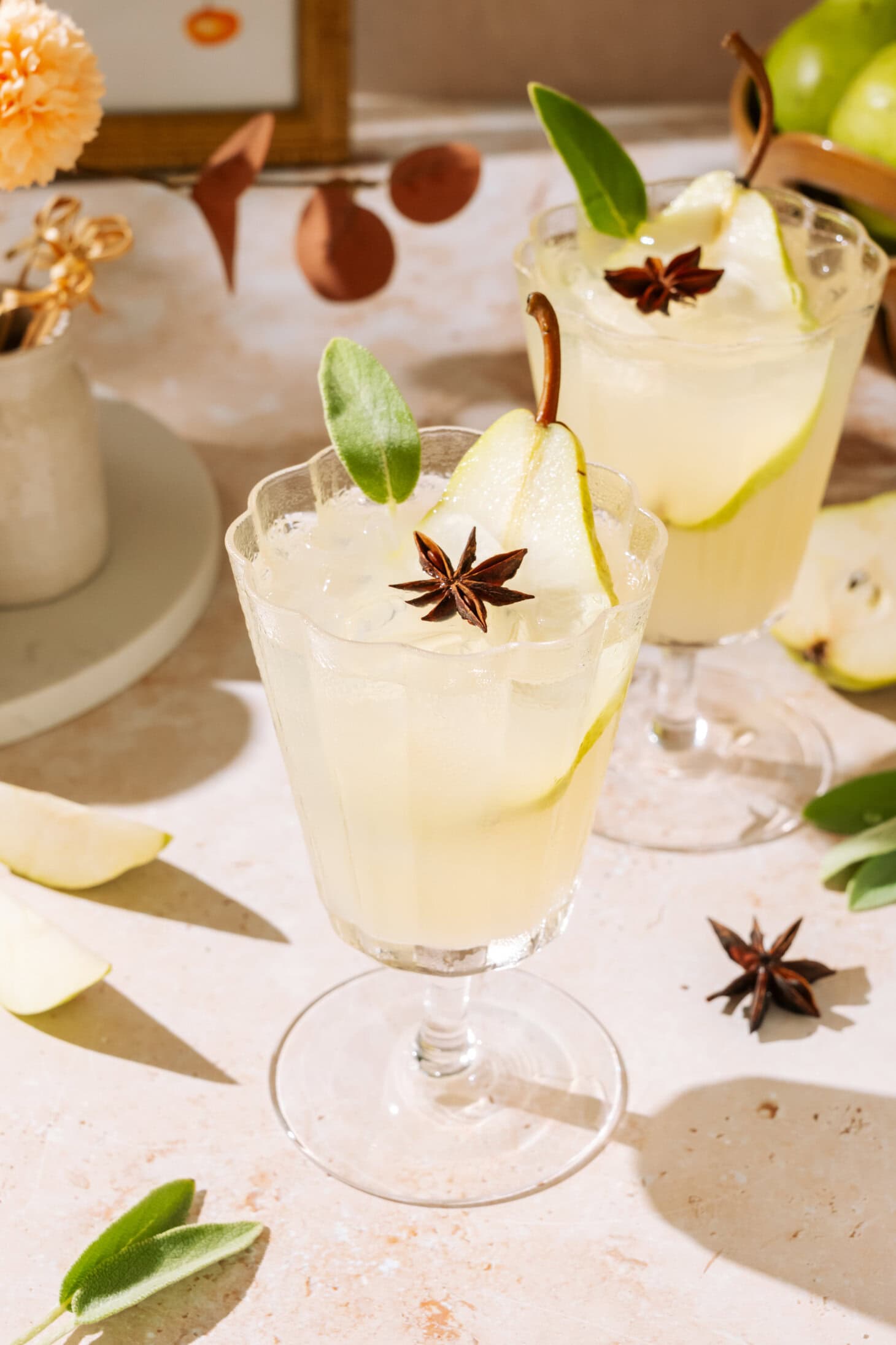 Pear White Wine Spritzer in stemmed glasses, garnished with fresh pear, sage, and star anise.