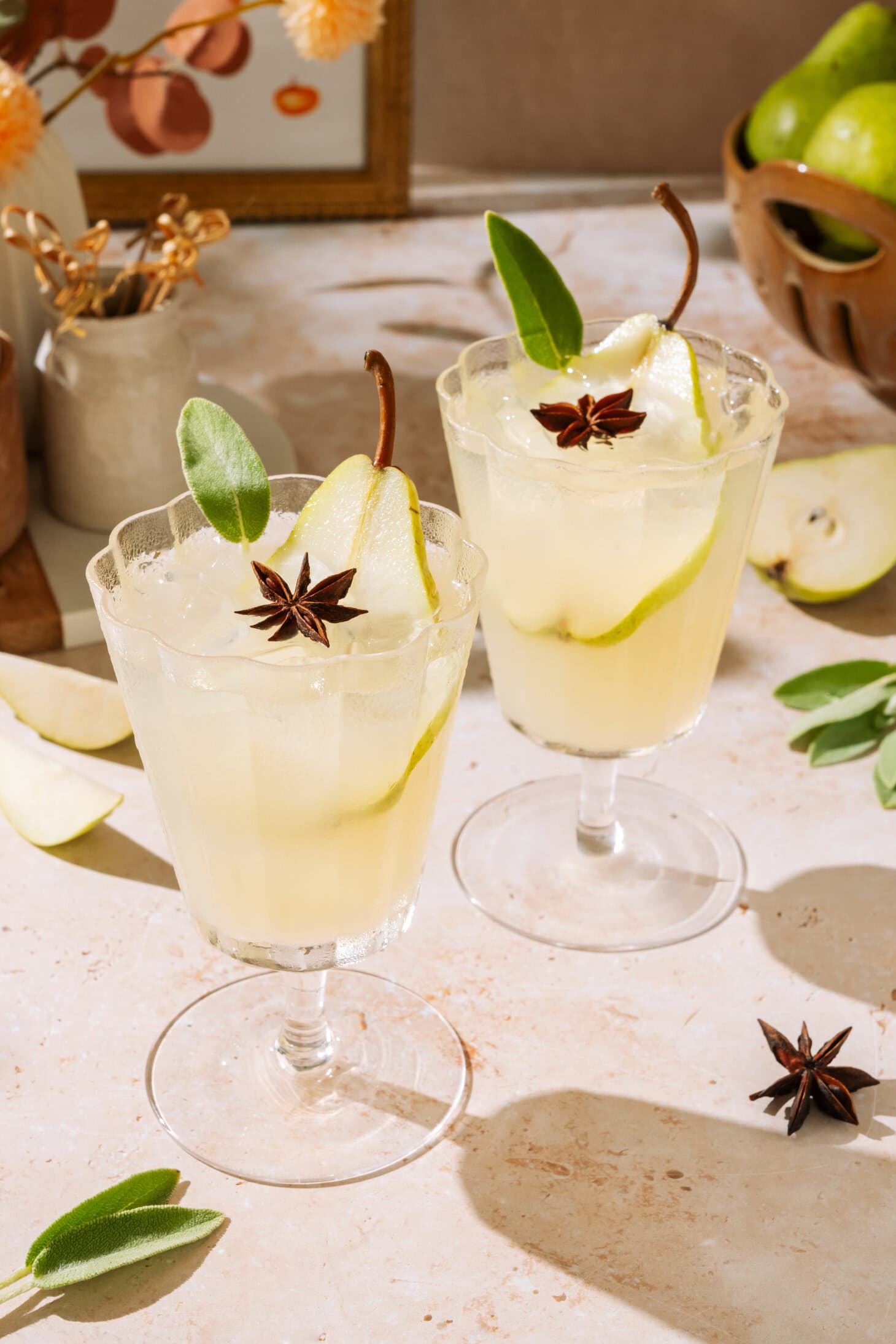 Pear White Wine Spritzer in stemmed glasses, garnished with fresh pear, sage, and star anise.
