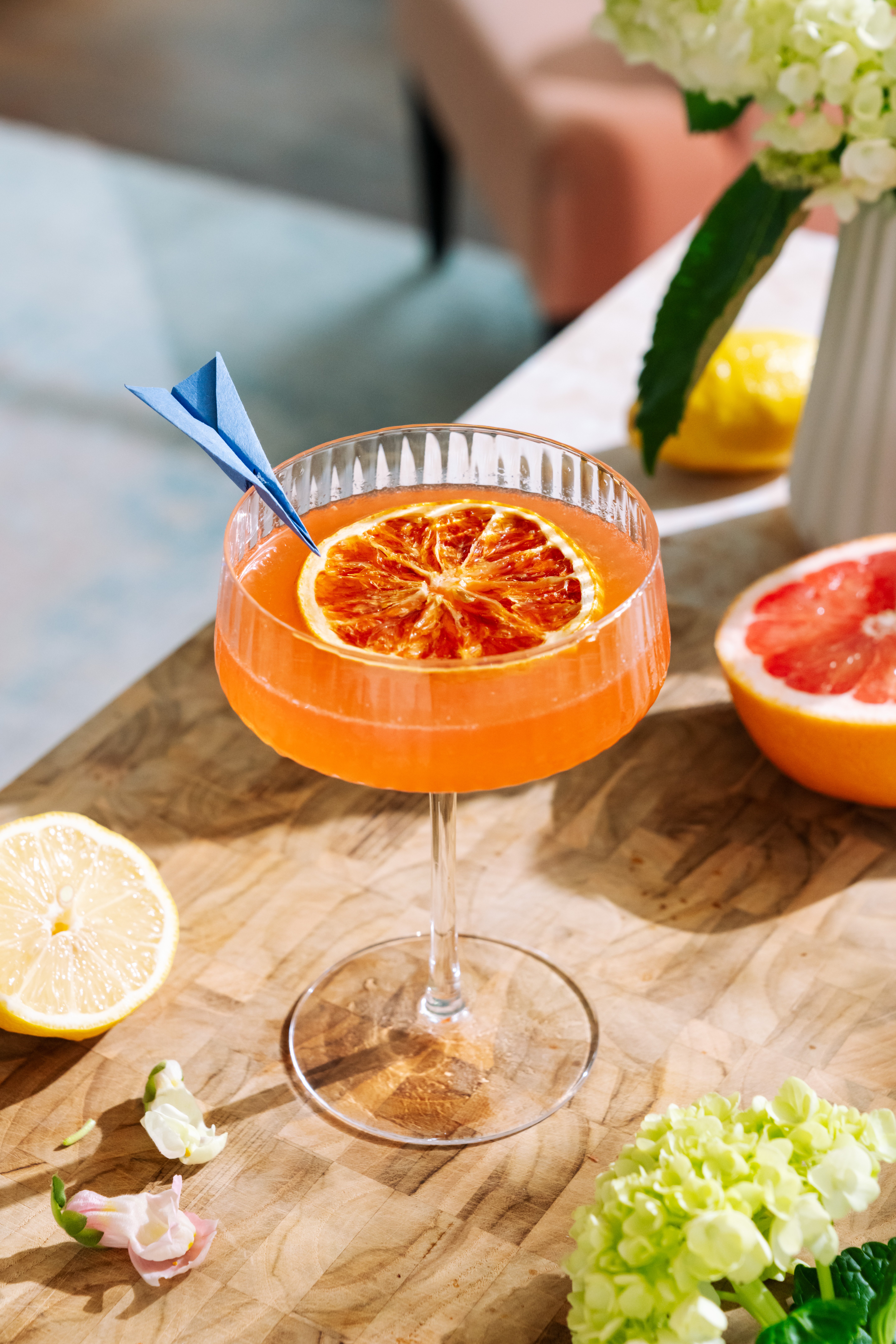 Vibrant orange cocktail with dried citrus slice garnish on a wooden table.