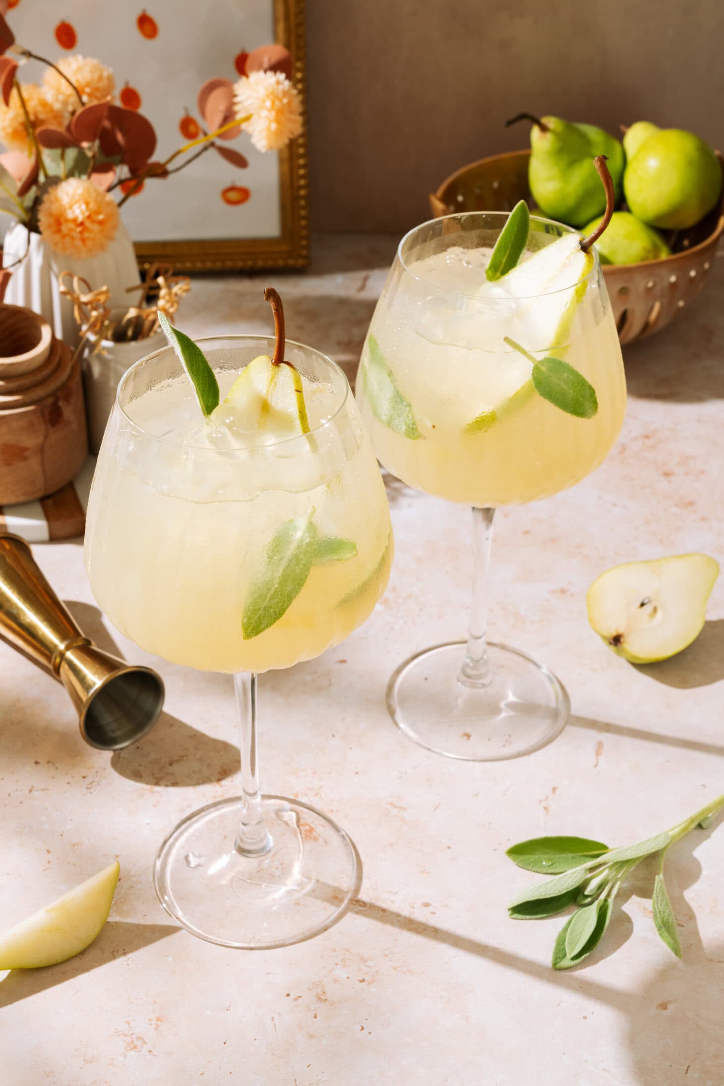 Two pear cocktails garnished with green leaves, served in elegant glasses on a stylish bar counter.