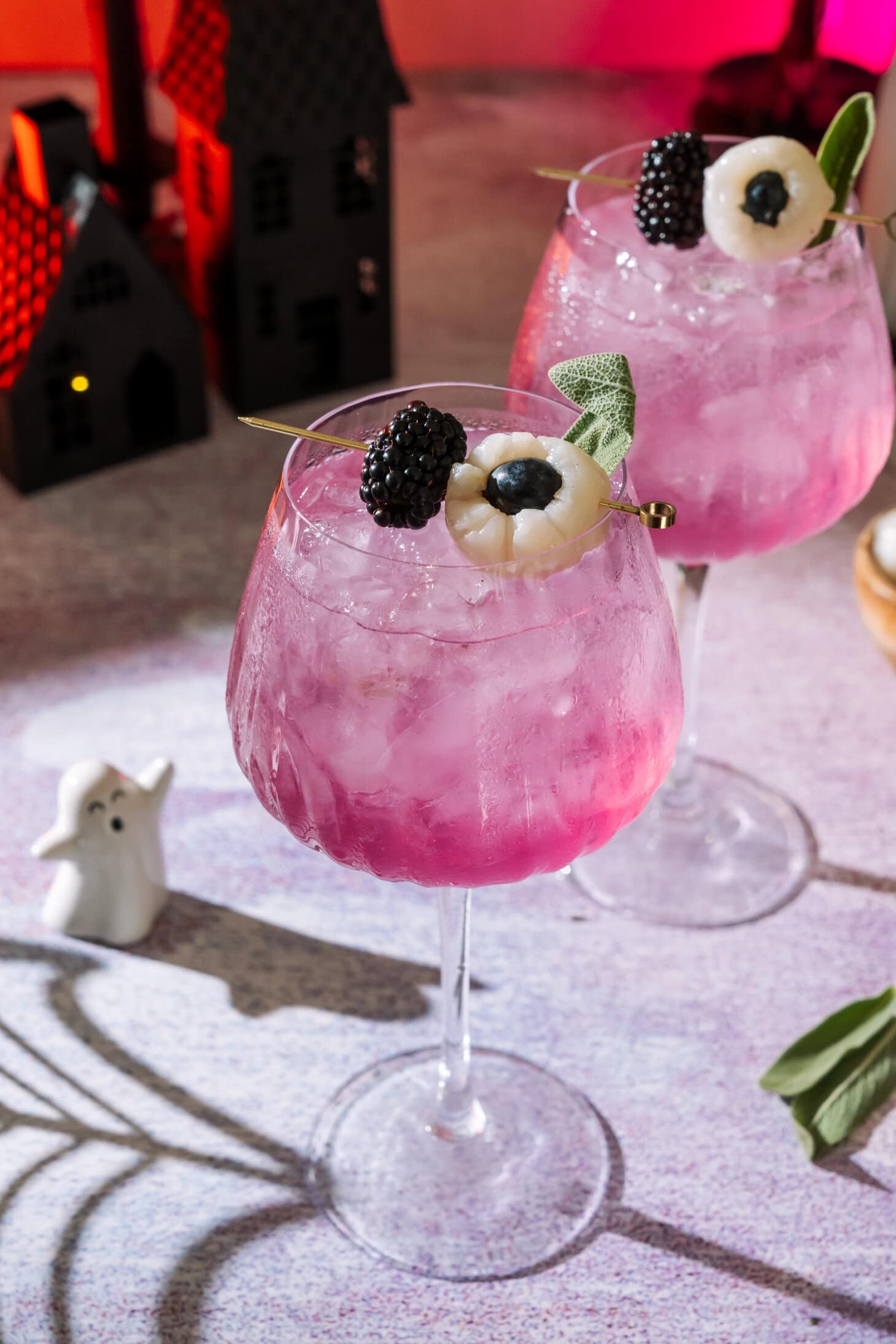Pink cocktail drinks garnished with blackberries and blueberries in elegant glasses.