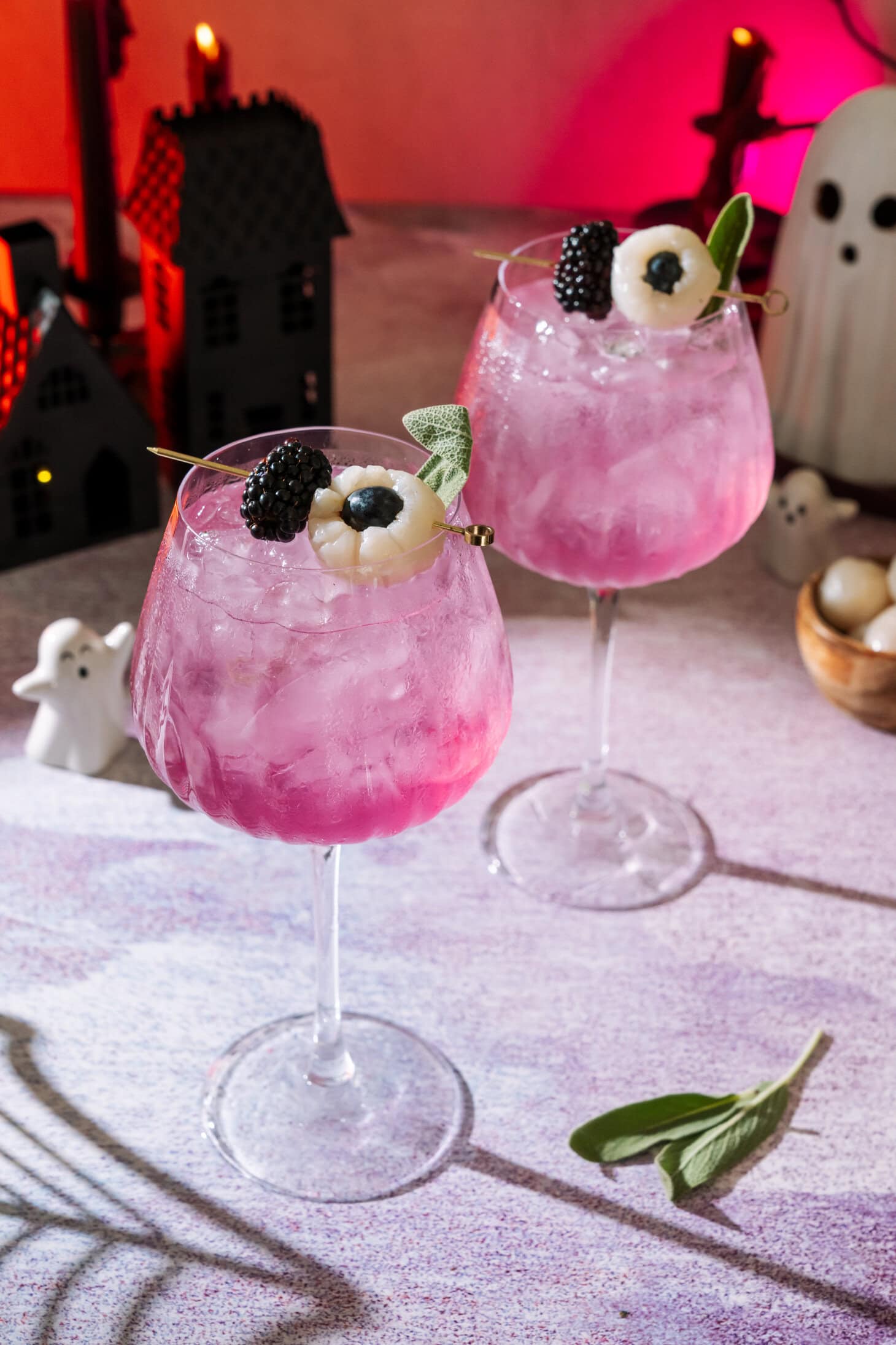 Two halloween themed Spooky Sarti Spritz cocktail drinks garnished with blackberries and blueberries in elegant tall glasses.